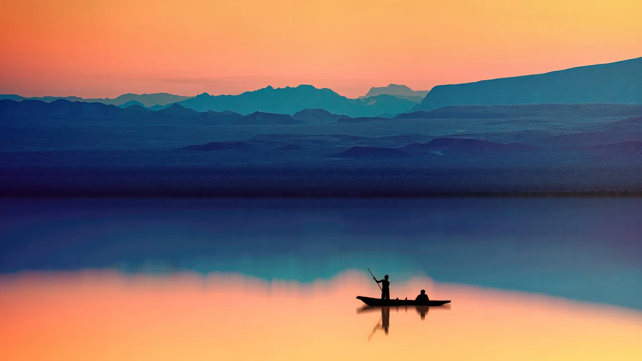 Fisherman in boat with mountain backdrop